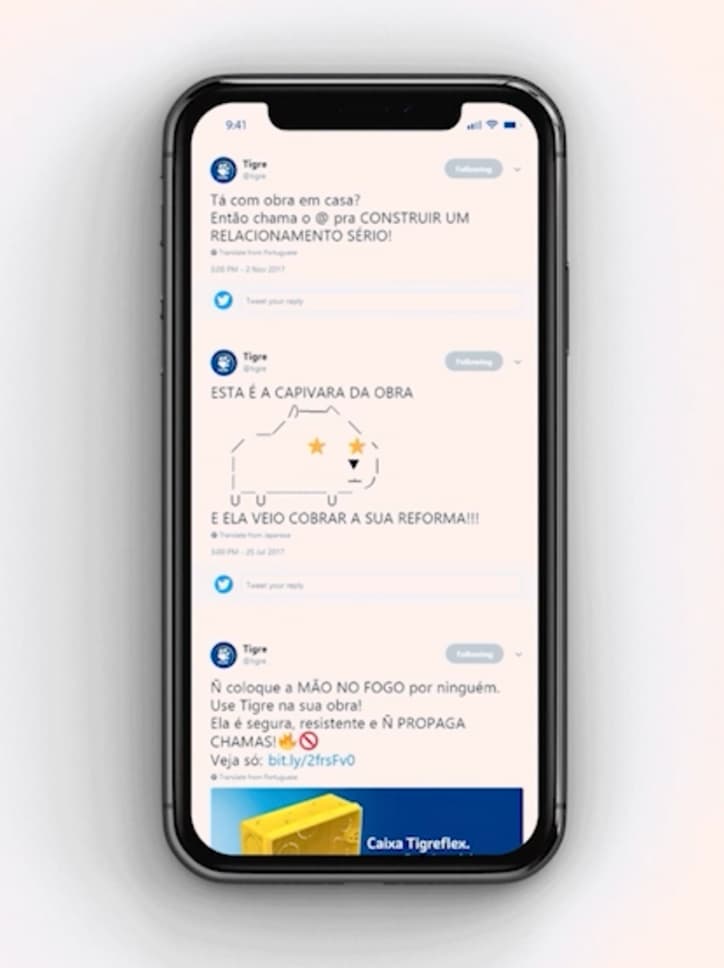 Mockup de um celular exibindo diversos tweets do perfil da marca Tigre, incluindo uma "capivara da obra" em ASCII art.